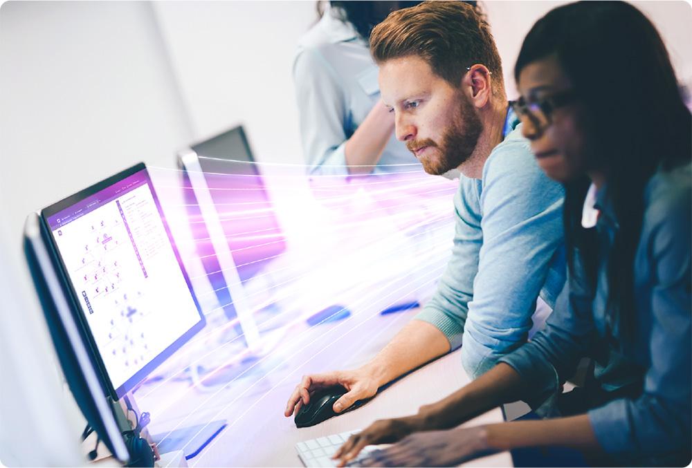 Two people work intently at computers, surrounded by dynamic, colorful streaks suggesting fast-paced digital activity.